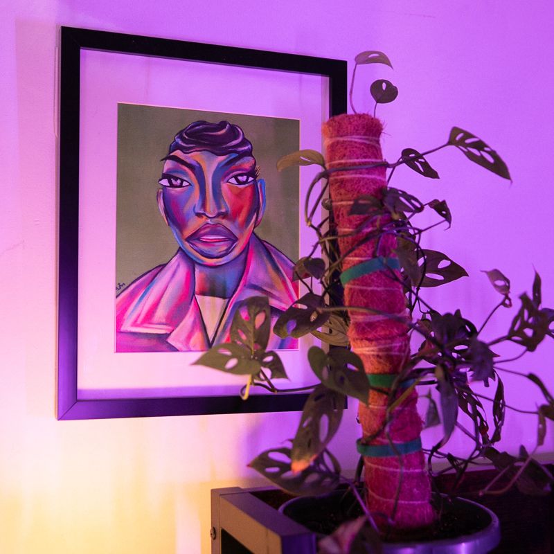 A painting of Boston Chery, hanging on her wall, with a plant in the foreground.